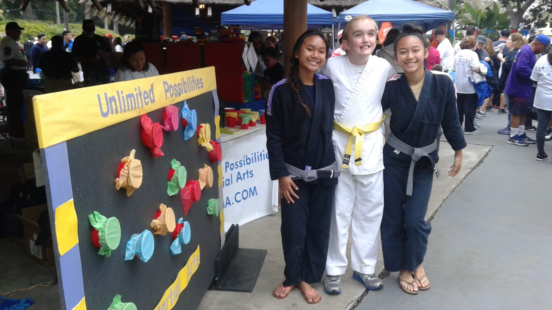 Three people posing for a picture in front of a sign.